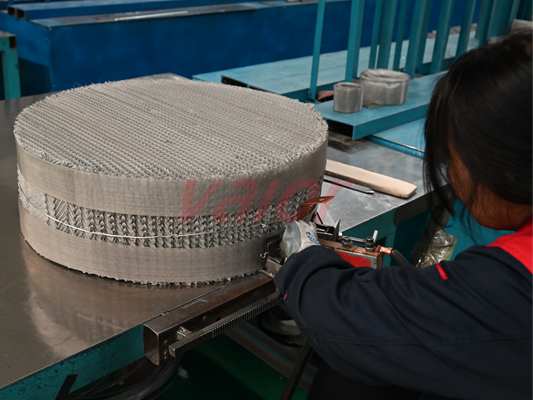 A female worker is finalizing a layer of wire mesh packing production.