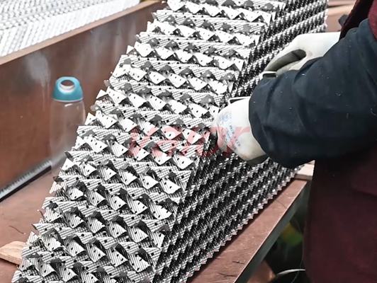 A worker is assembling a piece of metal sheet structured packing.